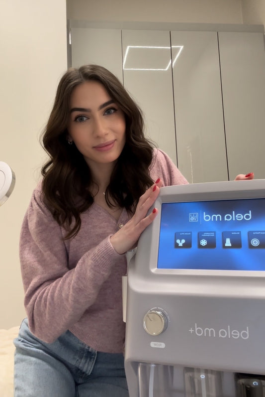 In this image, Sylvia from TS Skin Clinic in Oakville is featured, showcasing the Bela MD Facial Machine platform. She is describing the differences between the Bela MD Facial and HydraFacial treatments.